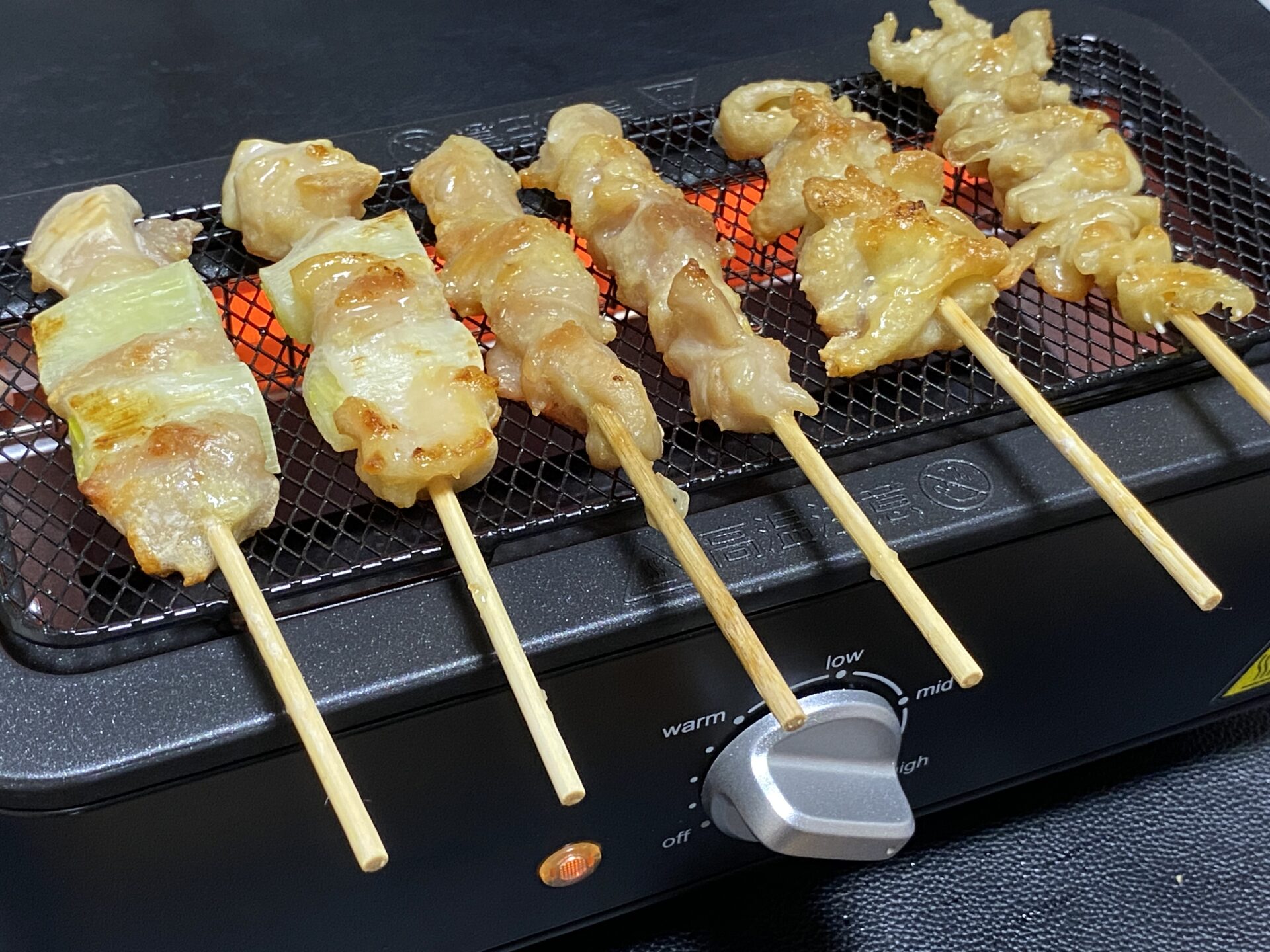 「山善の電気七輪 ESR-Q100 で焼いた焼き鳥。焼き目が付いた美味しそうなねぎま串と鶏皮串が、電気七輪の上でじっくり焼かれている様子。