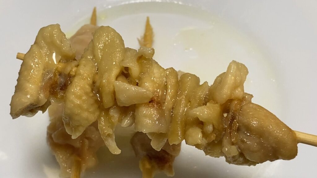 電子レンジで加熱された鶏皮串。脂っぽく、表面がベタつき、皮が柔らかくなってしまっている。