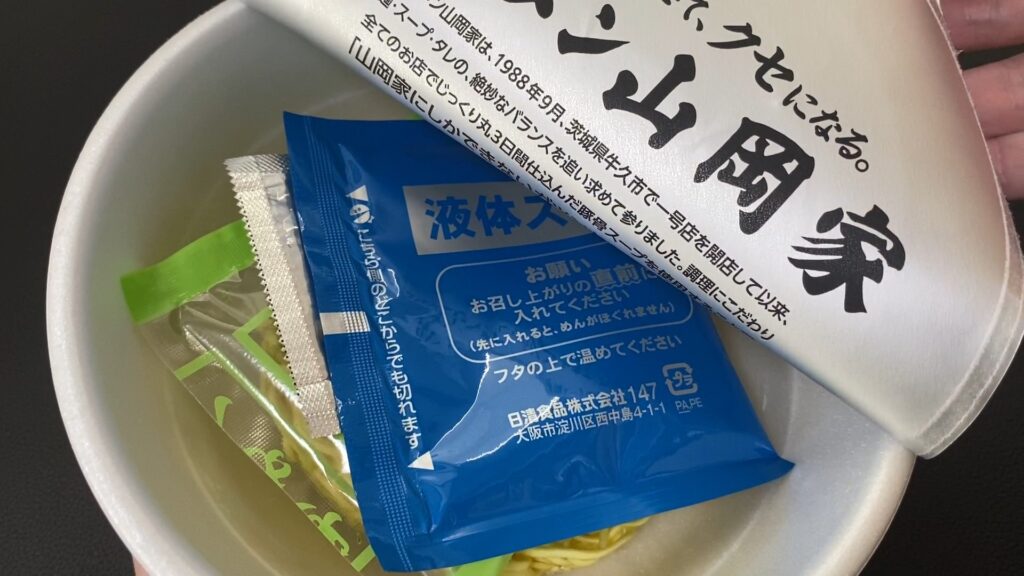 山岡家カップ麺の蓋を剥がし、内部を見せる画像。カップの中には麺が見えている。