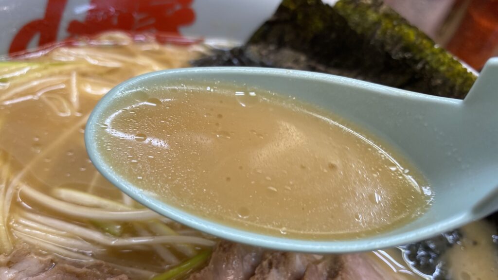 山岡家店舗で提供される醤油ラーメンのスープ。表面にはたっぷりの油が浮かび、濃厚な豚骨醤油スープが特徴