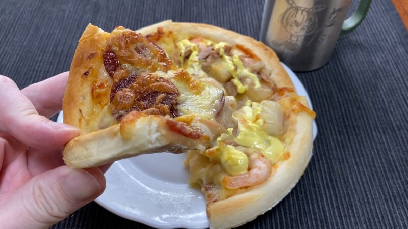 サラミと玉ねぎをトッピングした焼きたてピザのアップ写真
