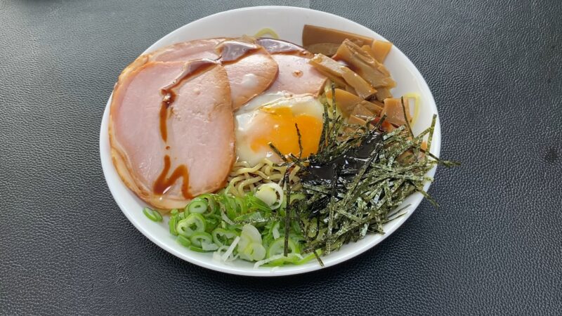 温泉卵、チャーシュー、メンマ、刻みネギ、刻み海苔をのせた汁なし風ラーメンの盛り付け