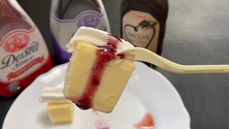ホイップクリームと濃い紫のブルーベリーソースをトッピングしたリッチチーズケーキ。濃厚な味わいが想像できる見た目。