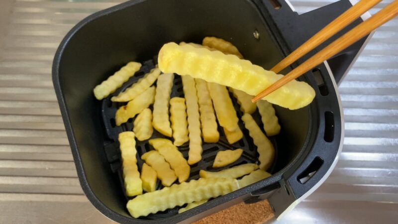ノンフライヤーで加熱したポテトを箸で持ち上げているところ