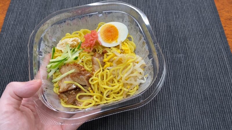 ローソン冷やし中華の完成品を手に持った状態。コンビニで手軽に楽しめる冷たい中華麺
