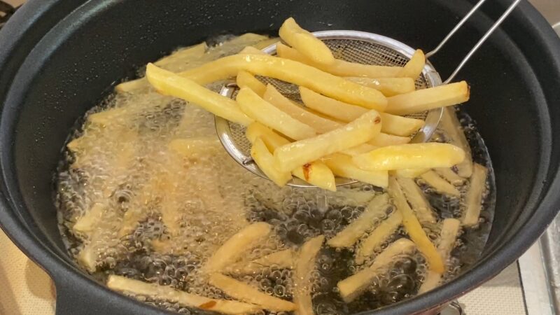 シューストリングポテトを油で揚げている途中の調理風景