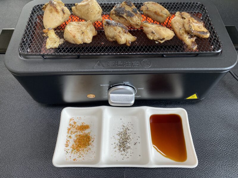 気七輪で串なし焼き鳥を焼いている様子と、手前に並んだ調味料3種(七味・塩・タレ)。