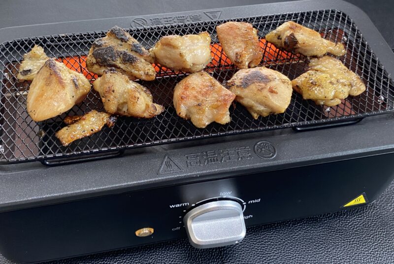 電気七輪の上で焼かれる業務スーパーの串なし焼き鳥。表面に焼き目がついている状態。