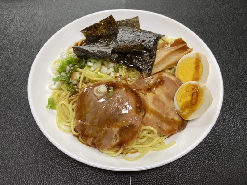 白い皿に盛られたまぜそば。海苔、チャーシュー、メンマ、味玉、刻みネギが麺の上にたっぷりトッピングされ、タレが絡んで艶やかに光っている。
