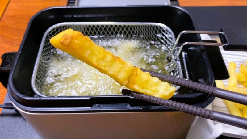 電気フライヤーで揚げたポテトを箸でつまんでロリ、ポテトは綺麗に揚げられている