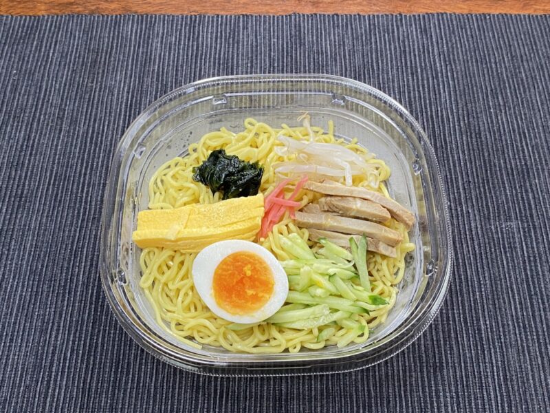 セブンイレブンの冷やし中華を器に盛り付け、錦糸卵やゆで卵、きゅうり、焼豚、わかめなどがきれいに並んでいる。