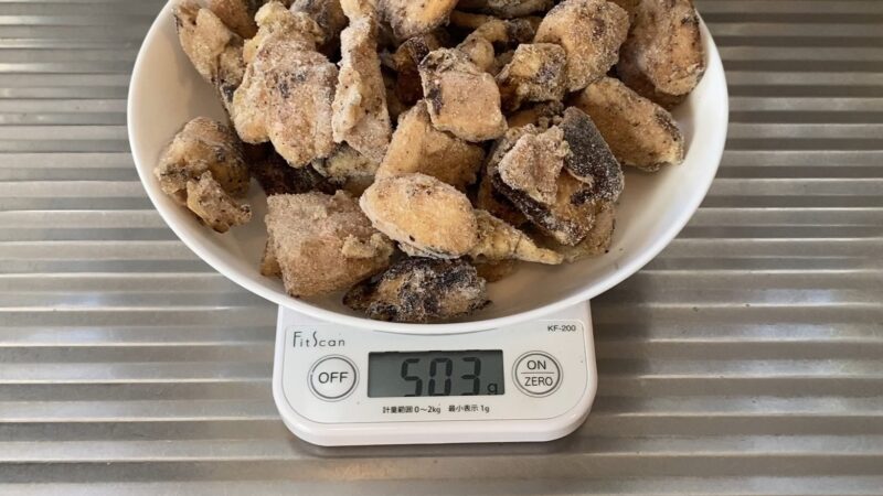冷凍状態の串なし焼き鳥を皿に乗せ、キッチンスケールで重さを測定中。表示は503g。