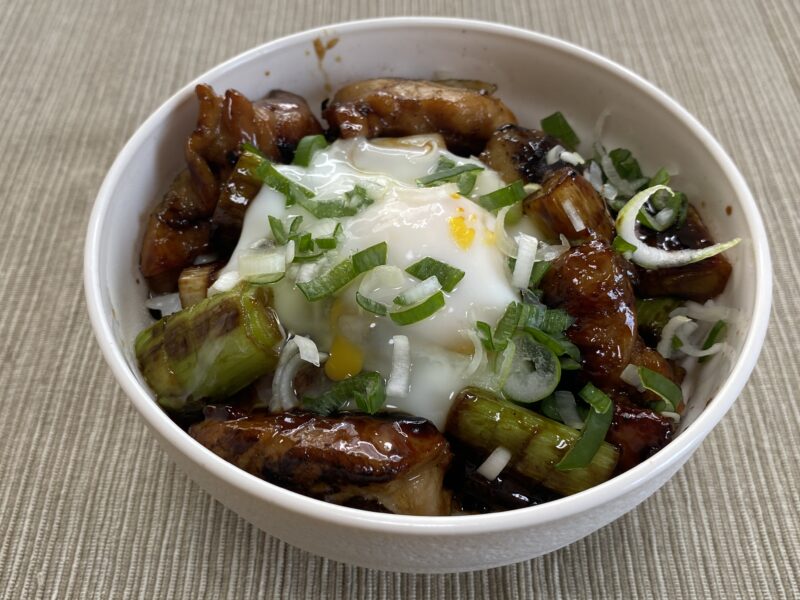焼鳥丼。ネギと甘辛タレで仕上げた焼き鳥に半熟卵を乗せた一品。