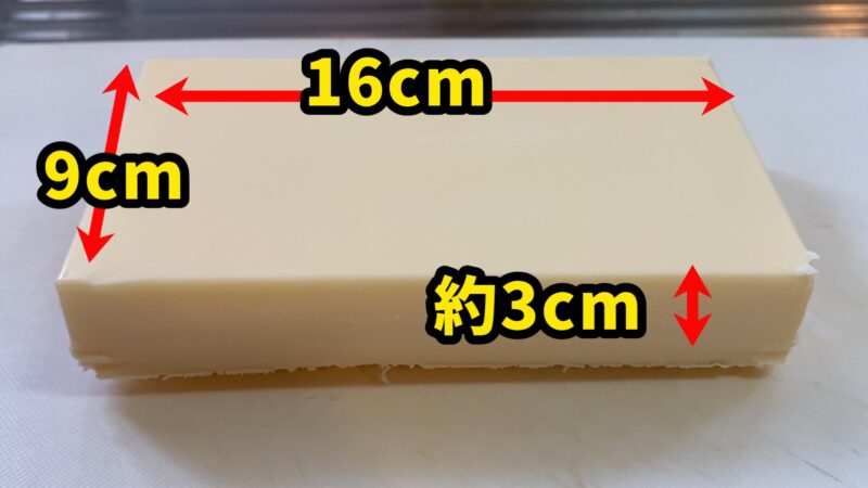 リッチチーズケーキのサイズを示す写真。縦9cm、横16cm、高さ約3cmの長方体。