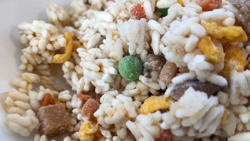 具材の中でひときわ目立つグリンピースに焦点を当てた冷凍炒飯の接写。凍った状態で米や卵、肉も確認できる。