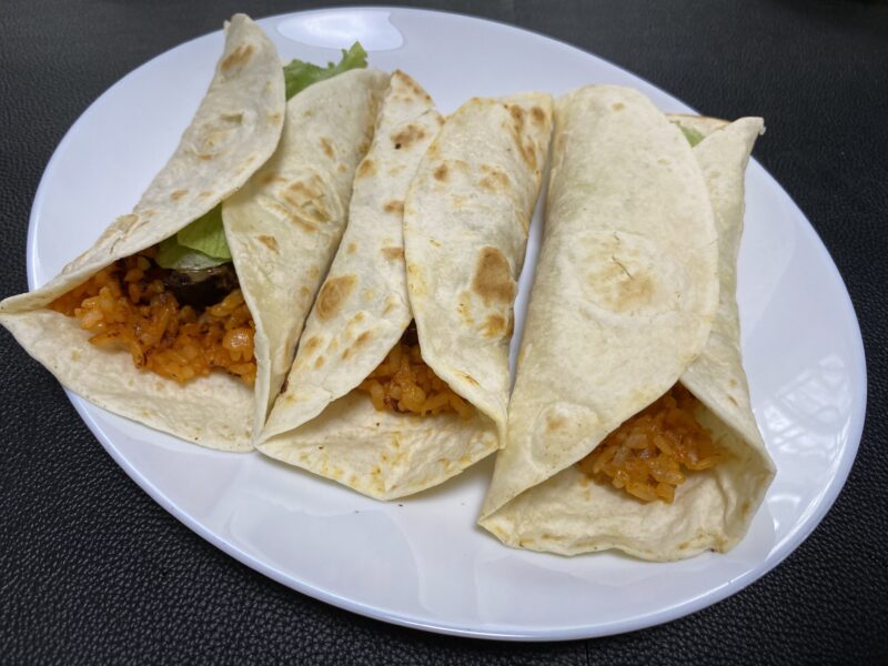 白い皿に並んだチキンライス入りのブリトー4本