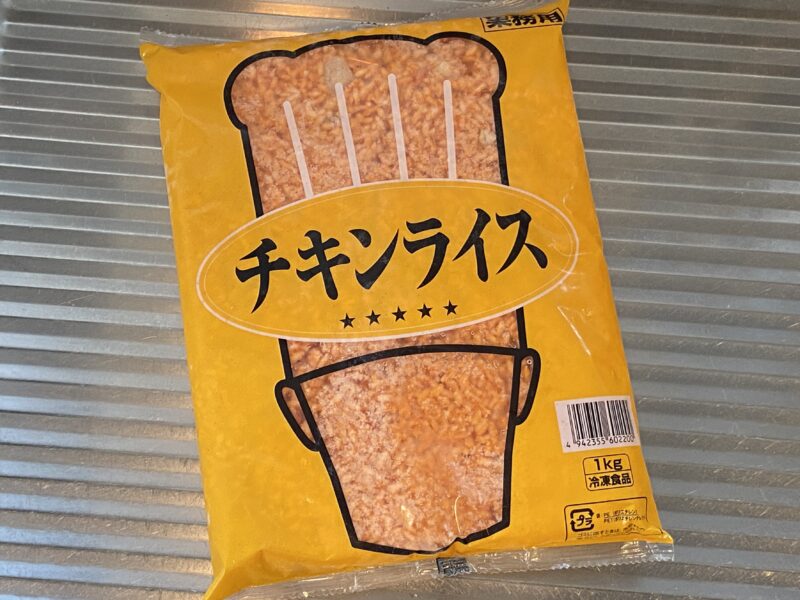 業務スーパーで販売されている「チキンライス1kg」のパッケージ。黄色地に大きな帽子のデザインが特徴。