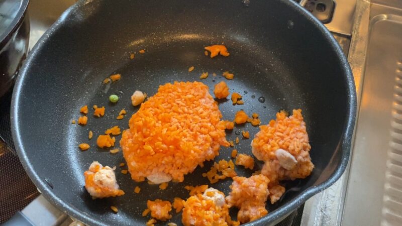 フライパンに凍ったチキンライスを投入した直後。まだ固まりのままで火が通っていない状態。