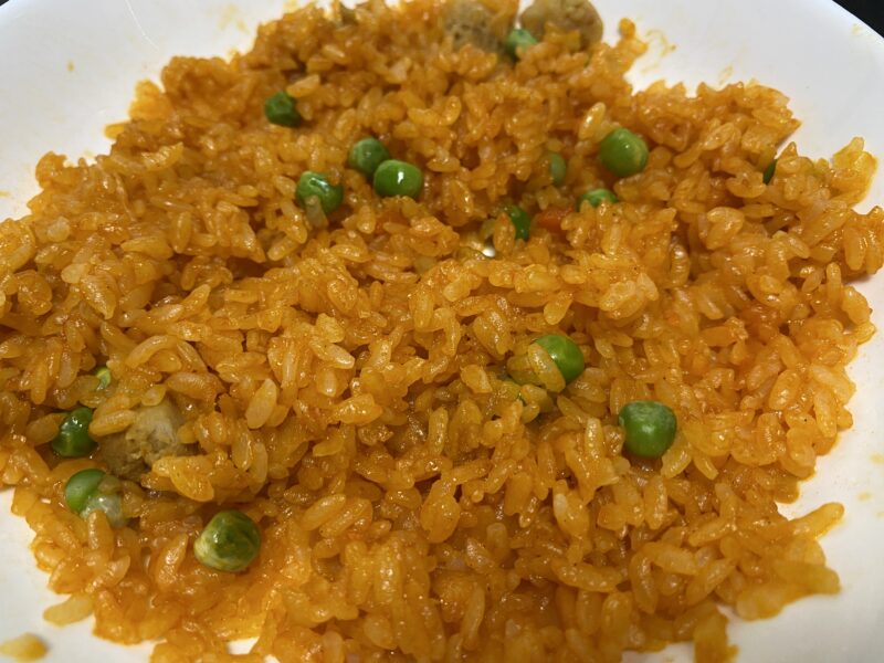 グリンピースが入った電子レンジ調理のチキンライスを皿に盛り付けた写真