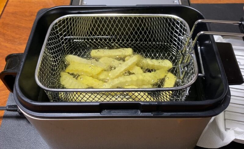 電気フライヤーにフライドポテトを投入する