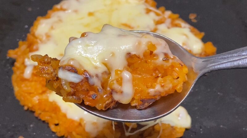 チーズ焼きチキンライスの一部をスプーンですくったアップ写真