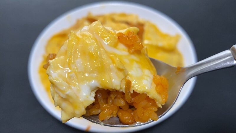 とろとろの卵がかかったチキンライスをスプーンですくった写真