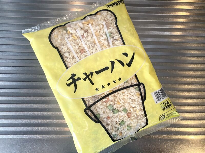 冷凍状態のチャーハンパックを斜め上から撮影。袋の中にはグリンピースや卵、チャーシューなどが確認できる。