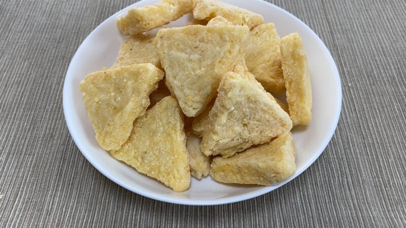 ：開封して皿に盛り付けたチーズポテト。三角形に成形された冷凍ポテトが複数並んでいる。