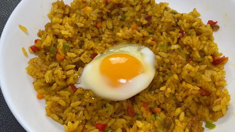 ドライカレーの中央に温泉卵をトッピングしたアレンジ料理。カレーのスパイシーさと卵のまろやかさがマッチした見た目。