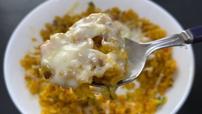 ドライカレーにピザ用チーズを加えて電子レンジで加熱したアレンジ。とろけたチーズが全体に絡んでまろやかになっている。