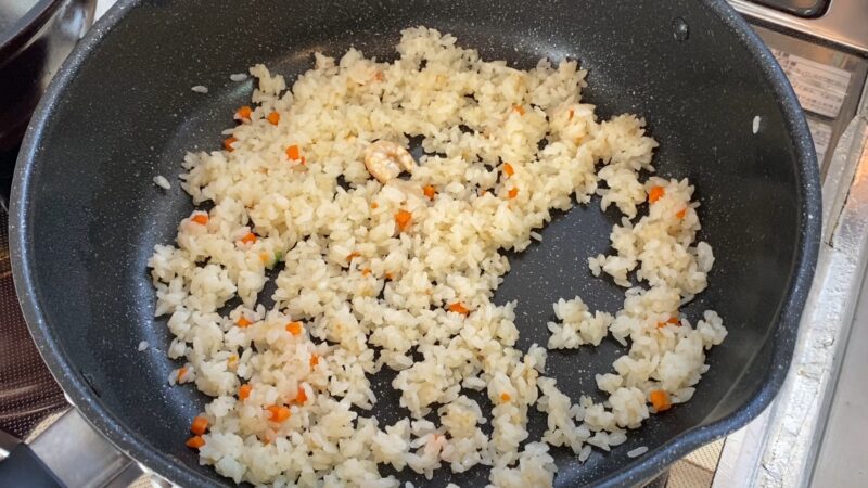 フライパンで炒めている途中のえびピラフ(野菜が見える)