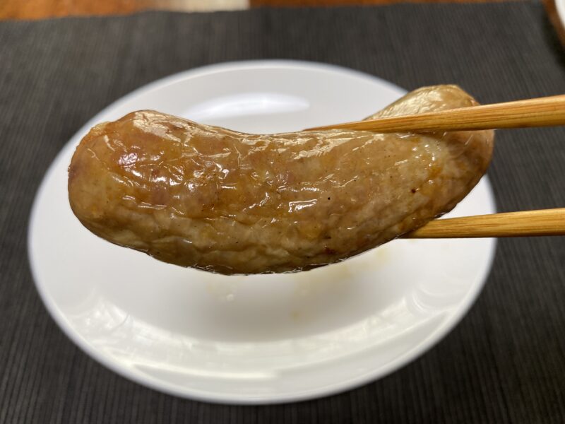 ノンフライヤーで調理した業務スーパー「こだわり生フランク」を箸で持ち上げた様子