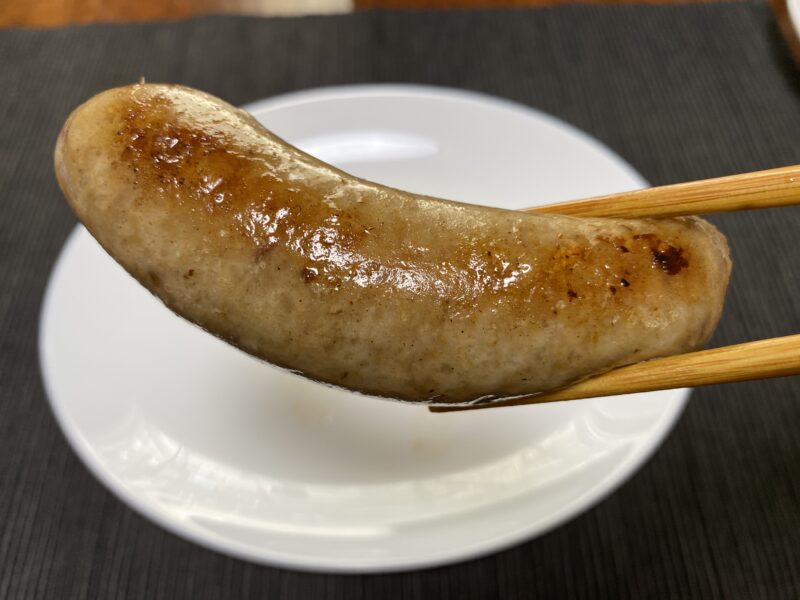 フライパンで焼いた業務スーパー「こだわり生フランク」を箸で持ち上げた様子