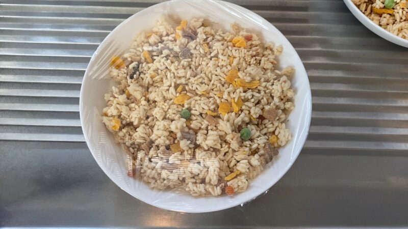 冷凍チャーハンを電子レンジにかける直前の状態。ラップがかけられたボウルがシンクの上に置かれている。