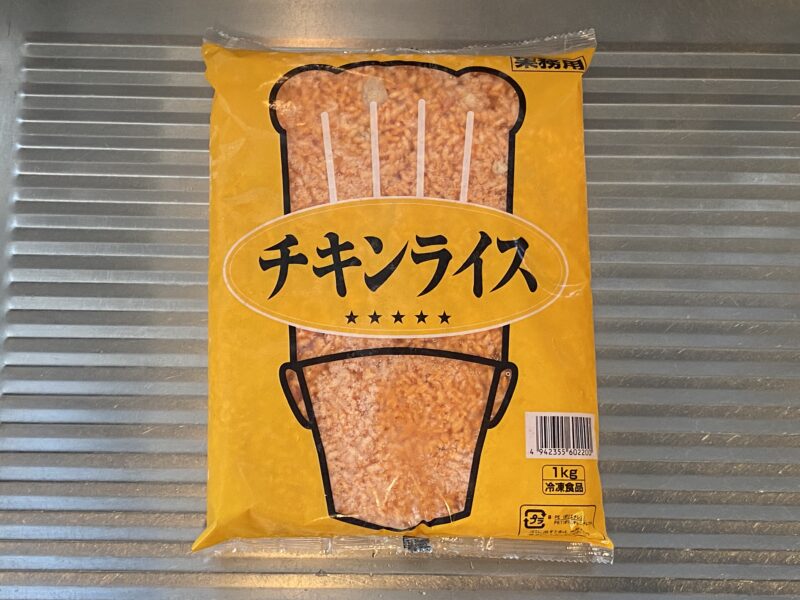 キッチンのシンク上に置かれた、業務スーパーの冷凍チキンライス1kgパッケージ。全体がきれいに写っている。