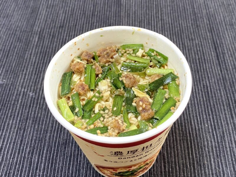 お湯を入れた直後のローソン担々麺。にらやねぎ、豚そぼろが表面に浮かび、香ばしさが広がる状態。