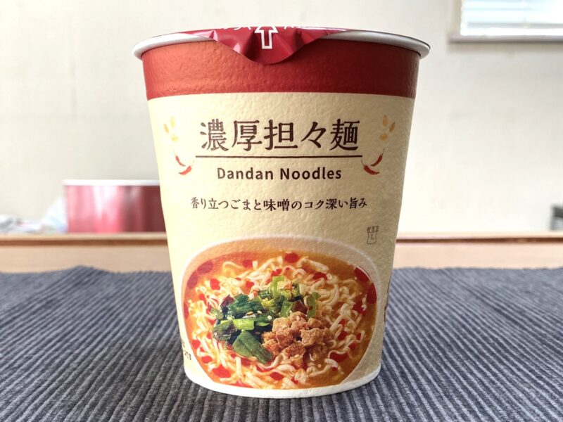 ローソンのカップ麺「濃厚担々麺」の正面パッケージ。白と赤を基調にしたシンプルなデザイン。