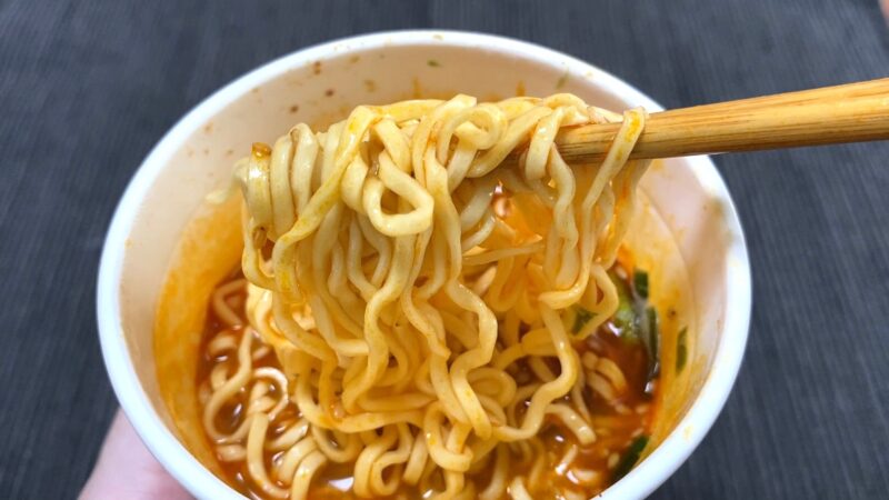 箸で麺を持ち上げている場面