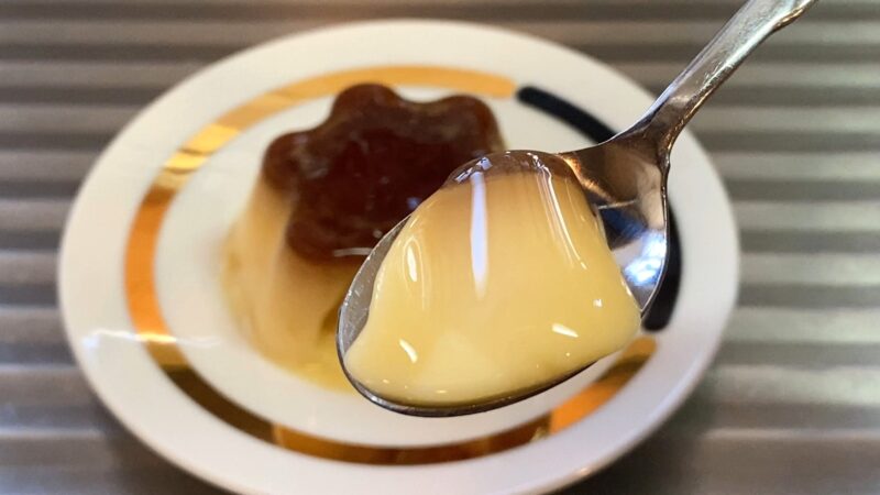 スプーンで一口すくった業務スーパー「練乳仕立てのマイルドプリン」、カラメルソースとプリンが一緒に映る