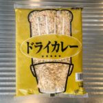 業務スーパーで販売されている「冷凍ドライカレー1kg」のパッケージ。黄色の袋にドライカレーが盛られた皿の写真が印刷されている。