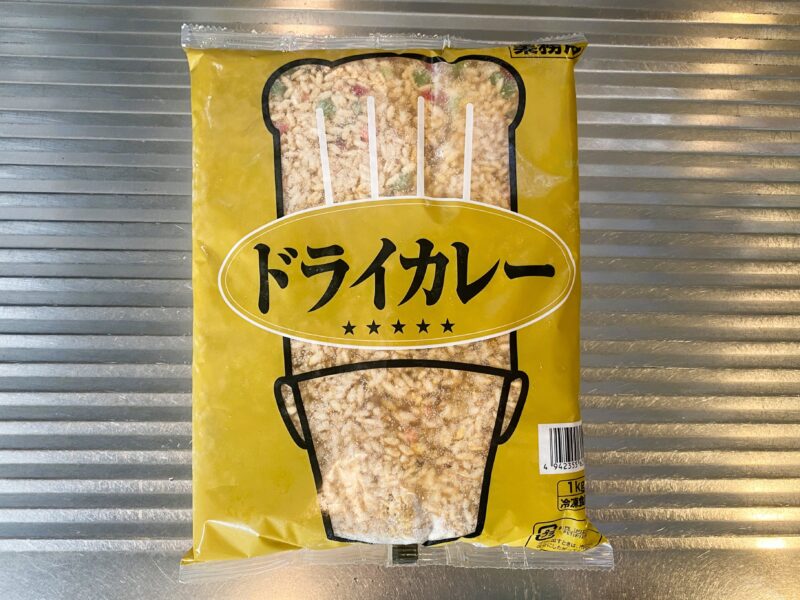 業務スーパーで販売されている「冷凍ドライカレー1kg」のパッケージ。黄色の袋にドライカレーが盛られた皿の写真が印刷されている。