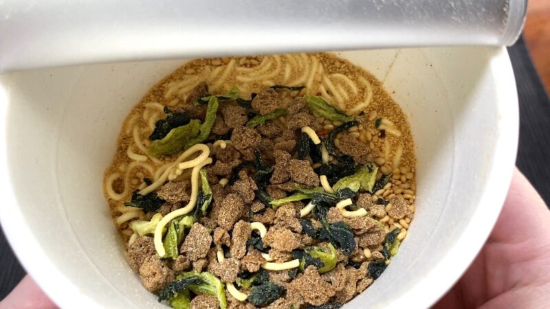 セブン担々麺の具材（ごま・肉そぼろ・青菜など）のアップ