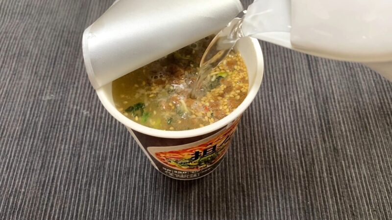 セブン担々麺にお湯を注いでいるシーン