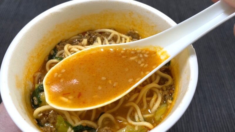 スープをレンゲですくい上げた様子。ごまが浮かぶ