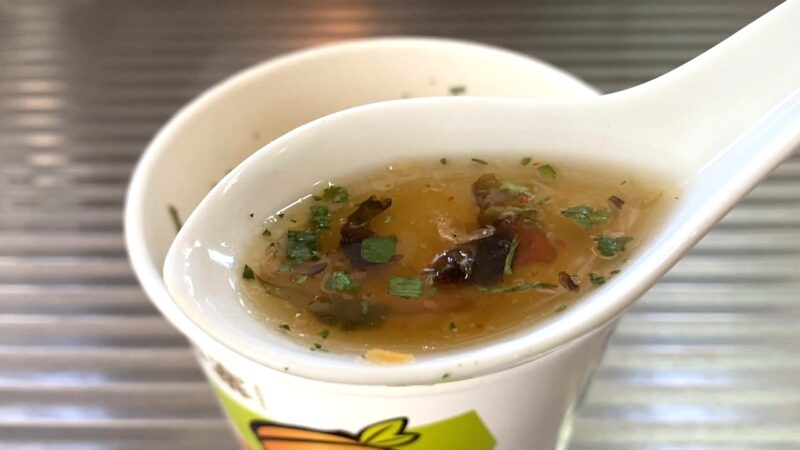 レンゲですくった酸湯面叶のスープ。香草やきくらげが浮かび、酸味と旨味が感じられる見た目。