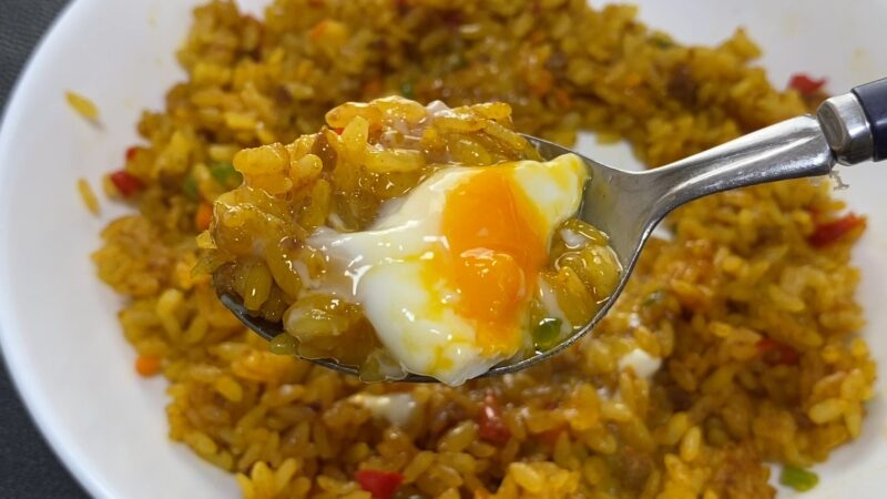 半熟卵がとろけるドライカレーをスプーンですくったアップ写真。黄身がごはんに絡み、濃厚でまろやかな印象。