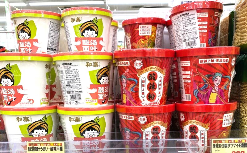 スーパーの棚に並ぶカップ麺。左側に和寨「酸湯面叶」、右側に赤いパッケージの「酸辣粉」が積み重ねられている。
