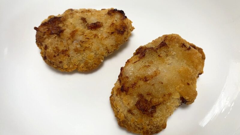 ノンフライヤーで加熱した「肉厚 極旨とんかつ」2枚を皿に盛った写真。表面に焼きムラがあり、焦げやすい部分と淡い色の部分が混在している。