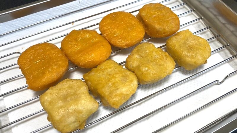 金網の上に並べたチキンナゲット。上段が海外製で濃いオレンジ色、下段が国産で淡い黄色の衣。