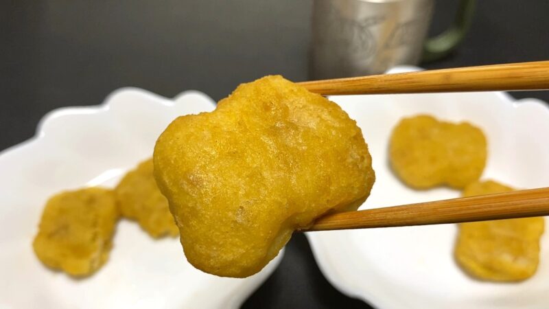 ノンフライヤーで加熱したチキンナゲットを箸で持ち上げた様子。油を使わずに程よく焼き色がついている。